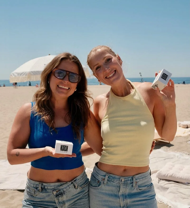 Two founders holding a custom premium coffee bag at the beach