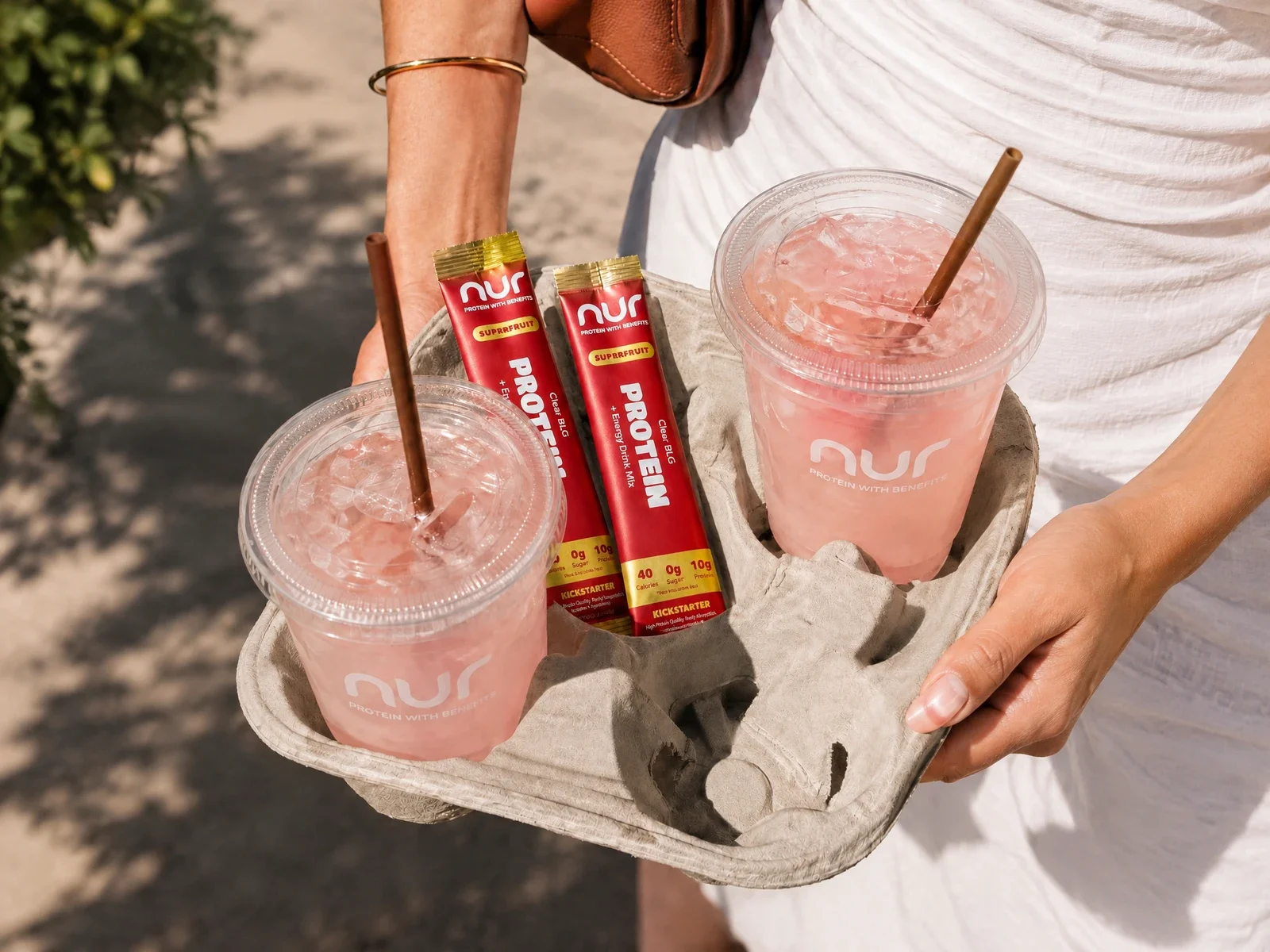 Protein stick packs beside pink drinks