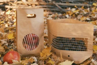 Two kraft paper pouches photographed outdoors with fruit