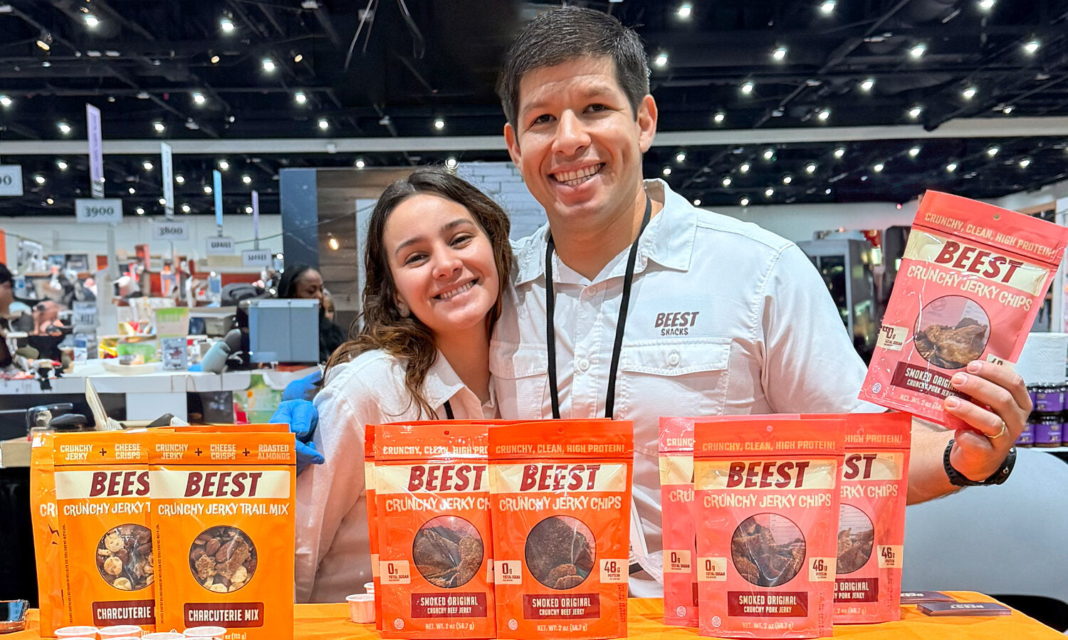 Lucas Prado and Nicole Ruiz at a BEEST booth with clear-window snack pouches.