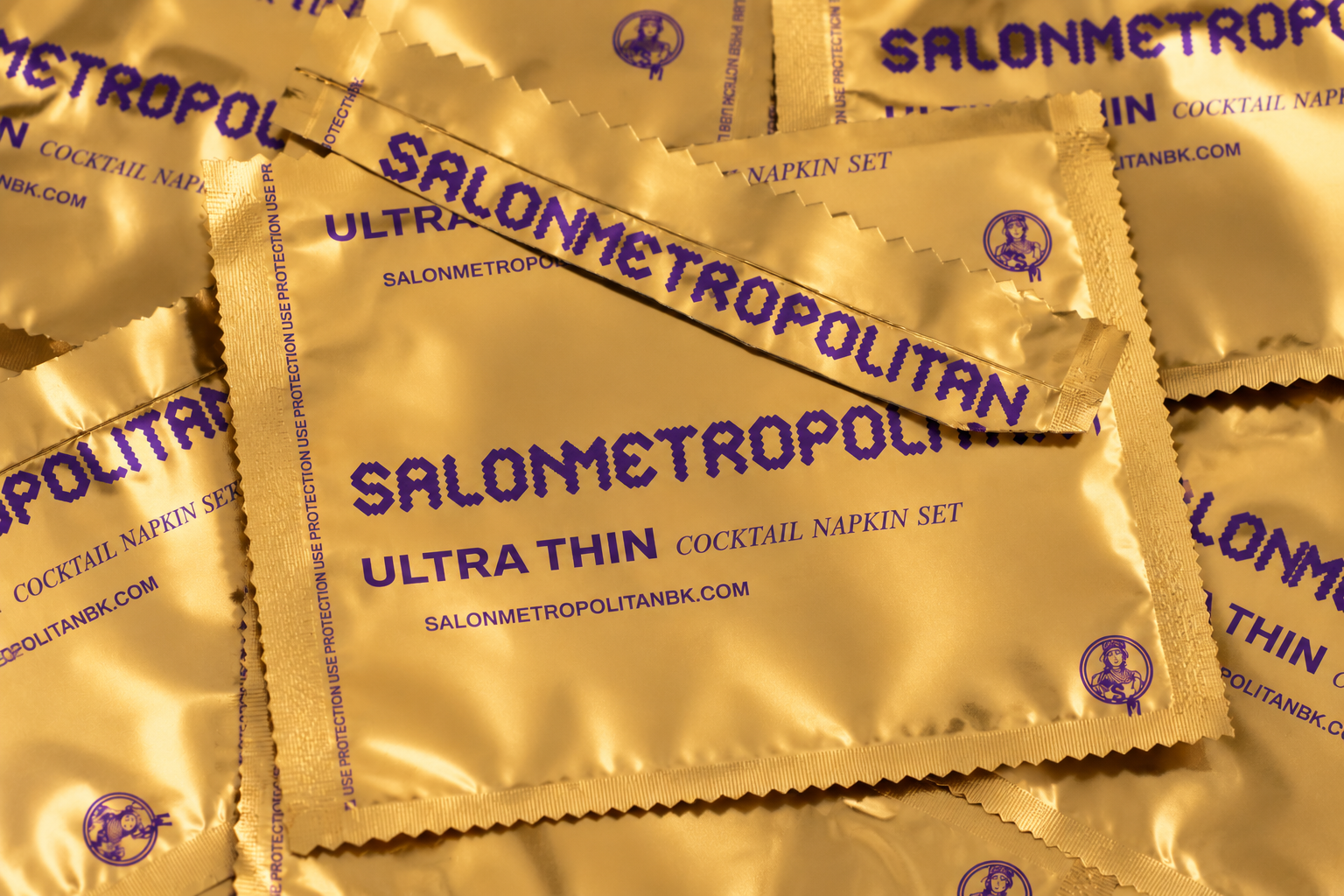 Gold Salon Metropolitan Ultra Thin cocktail napkin sachets overlap in a close-up product arrangement.
