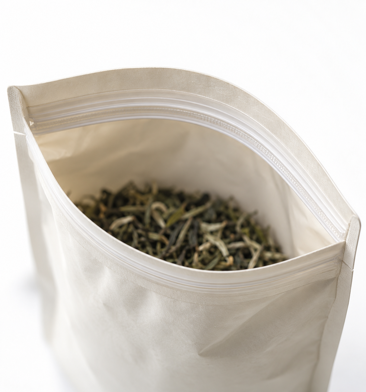 Close-up of an open ivory tea pouch with a reusable zipper and loose tea