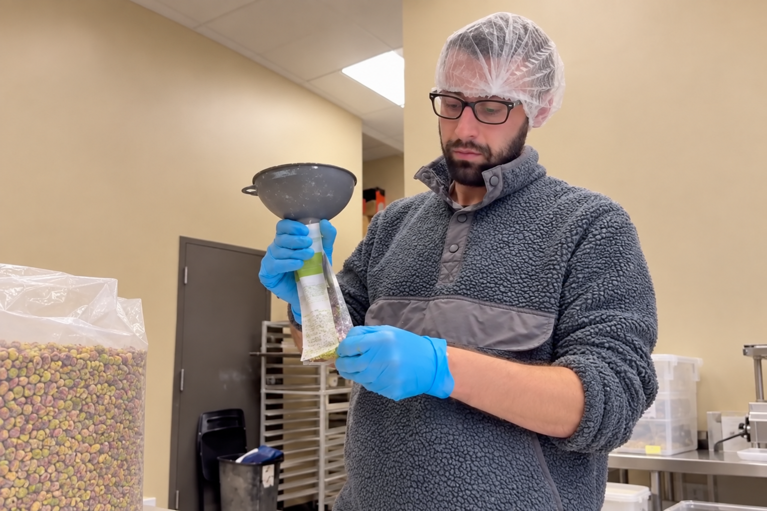 PHiSTiK founder filling a clear pistachio pouch in a production facility