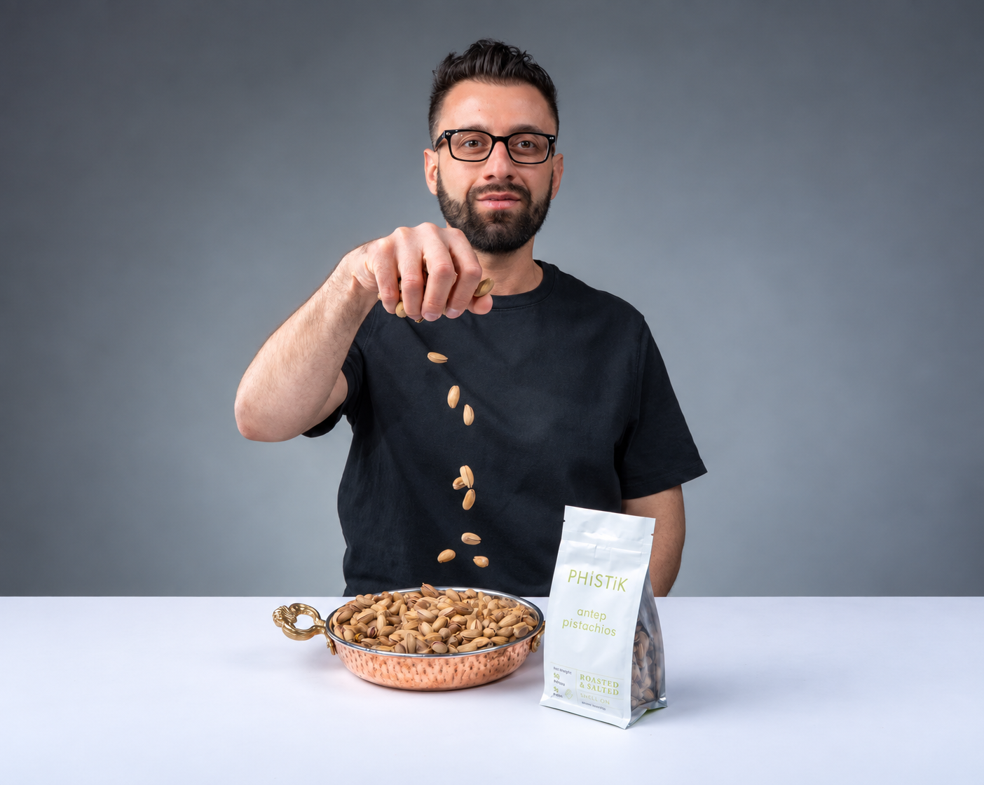 PHiSTiK founder dropping pistachios beside a product pouch