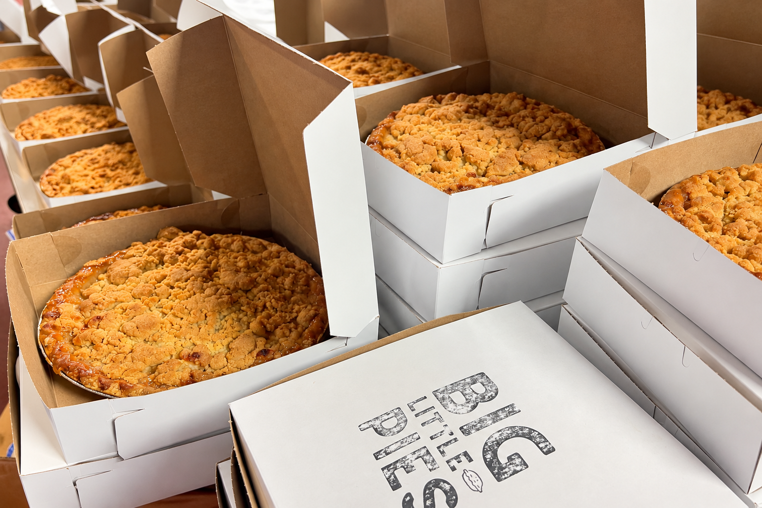 Freshly baked pies sit inside open white shipping boxes prepared for delivery.