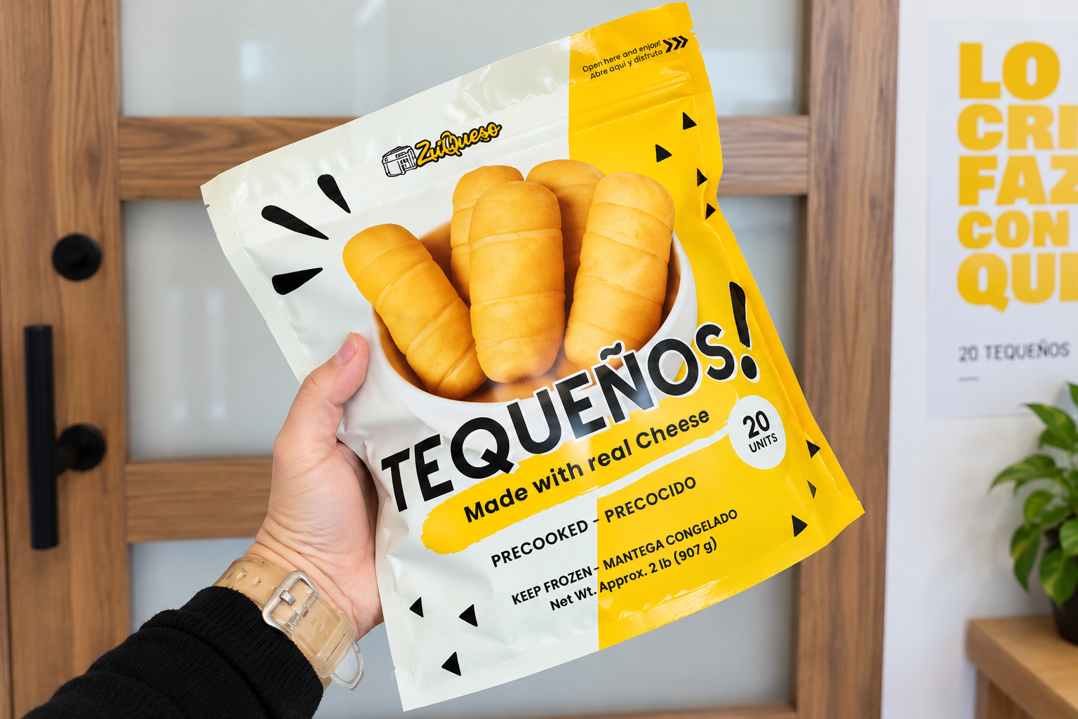 A hand holds a yellow and white Zuqueso Tequeños frozen food pouch.