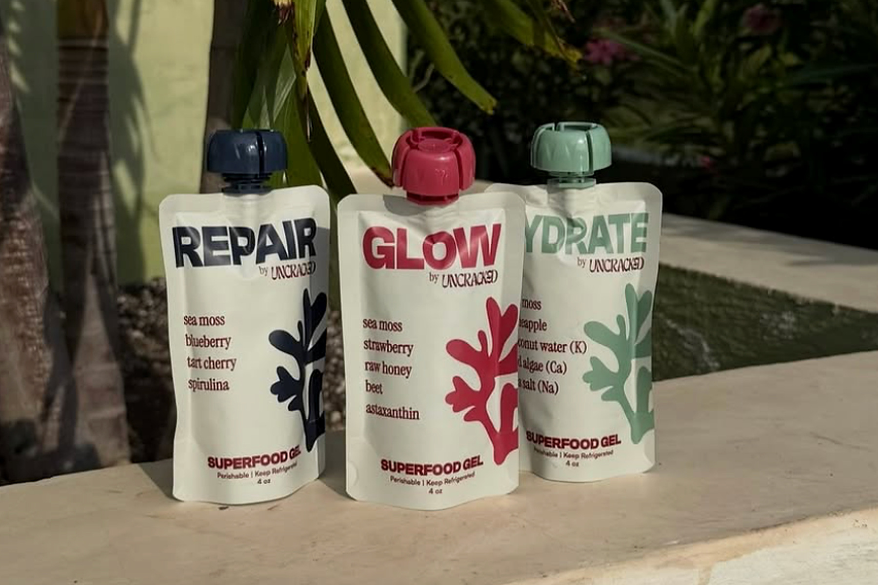 Uncracked Repair, Glow, and Hydrate spouted pouches stand together beside a pool.