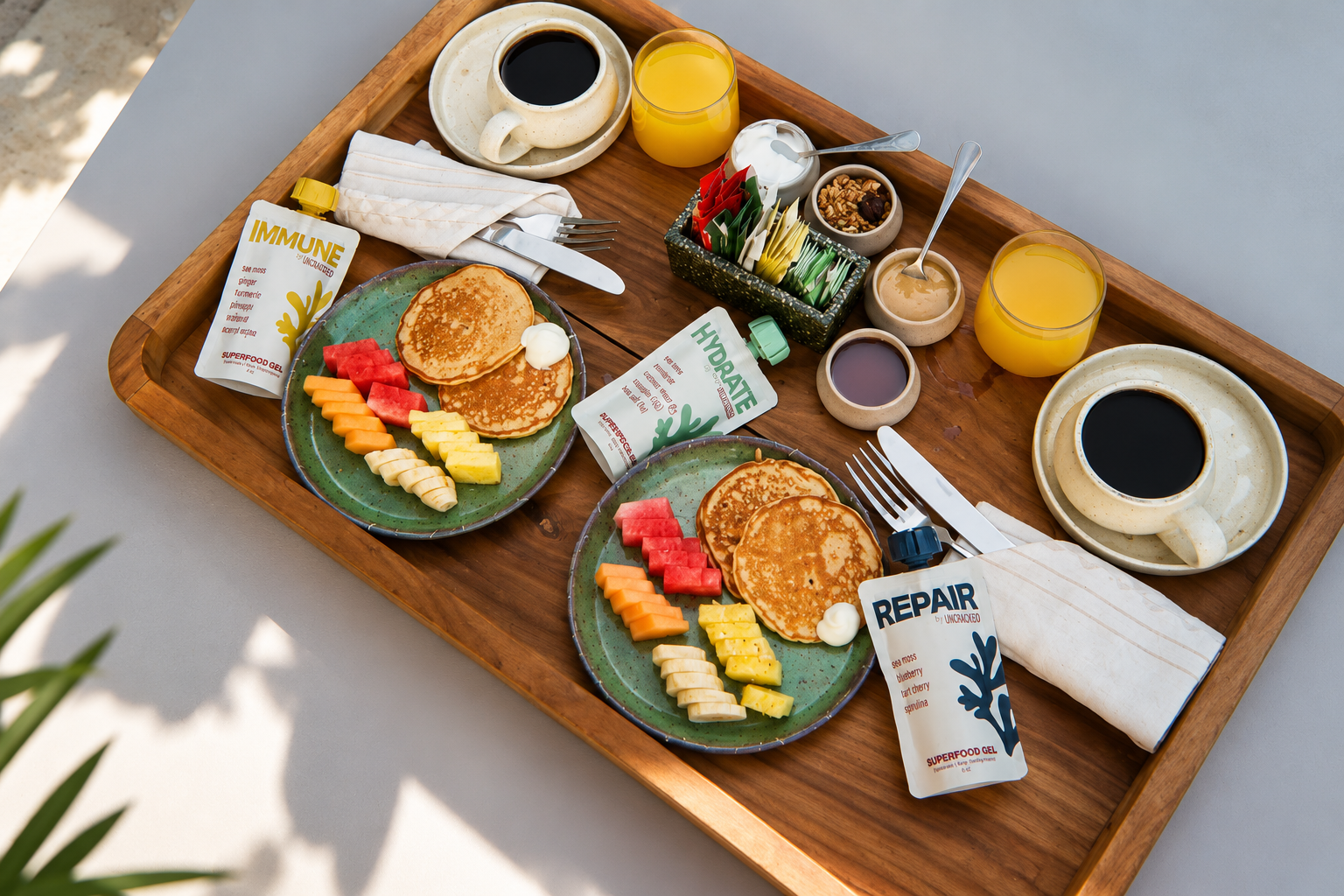 Uncracked wellness pouches are arranged with breakfast plates, fruit, juice, and coffee on a wooden table.