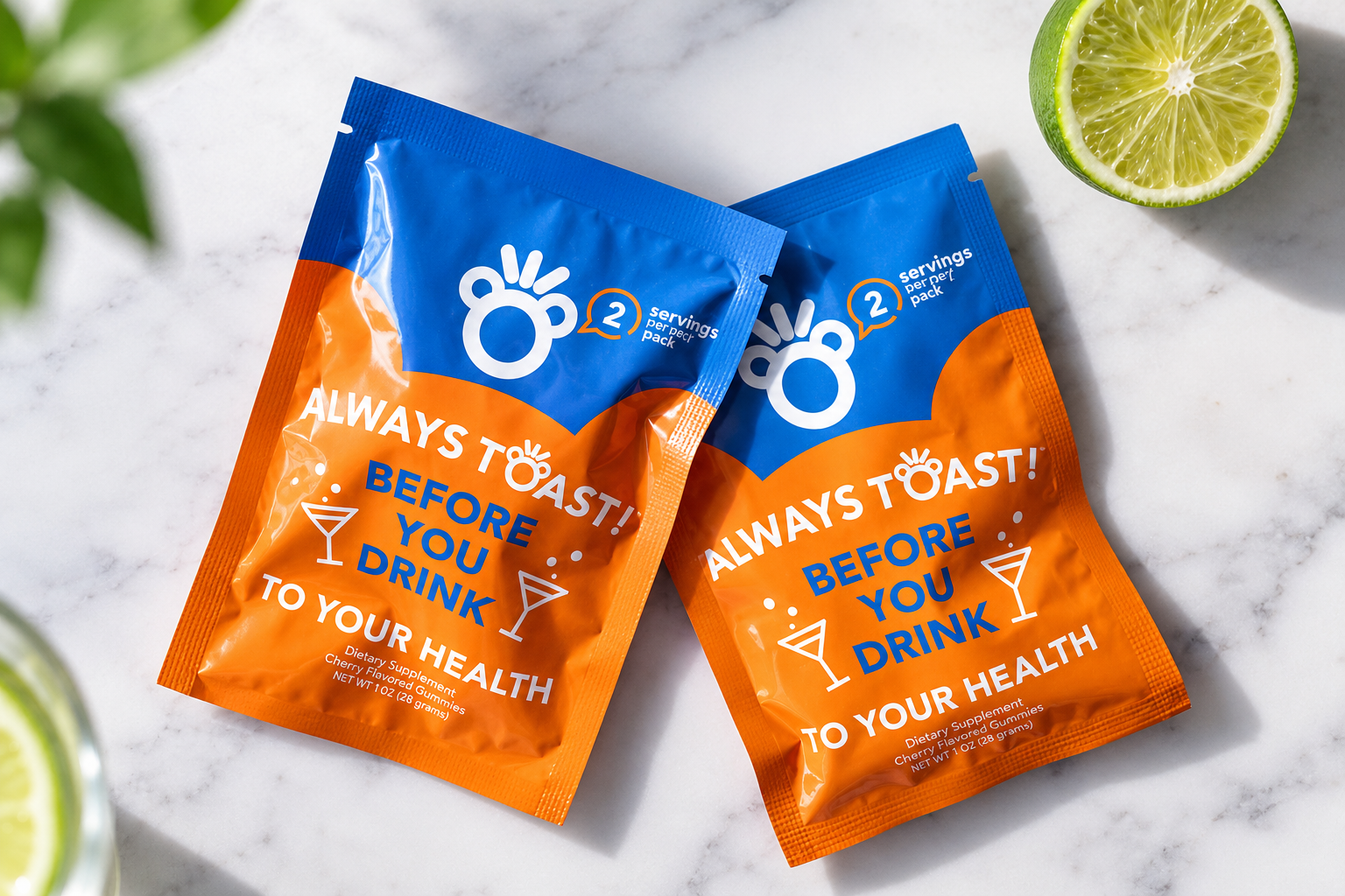 Two orange and blue Toast! supplement pouches are displayed on a marble surface beside a lime half.
