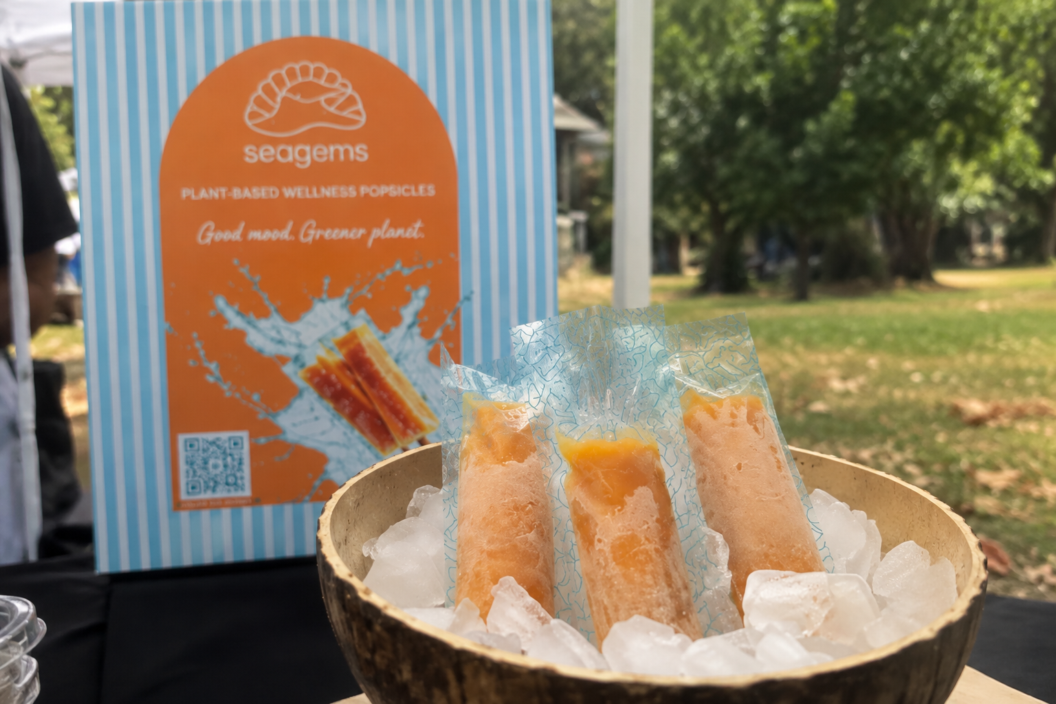 Sea Gems popsicles are displayed on ice beside a branded sign at an outdoor event.