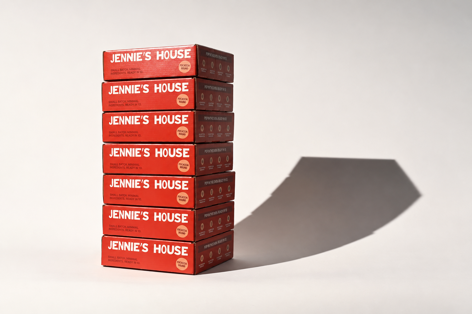 A stack of red Jennie's House focaccia cartons stands under studio lighting.